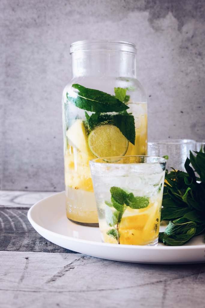 A pitcher of water and a couple glasses with mint and lemon slices. Water impacts the way we feel and function throughout the day and help us to sleep better at night.